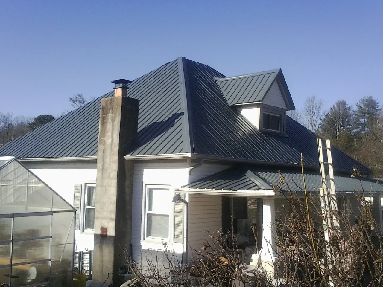 Dark blue standing seam metal roof on a white farmhouse with dormer — Slate & Tile Roof Repair by Roofing Brothers in Robertsdale