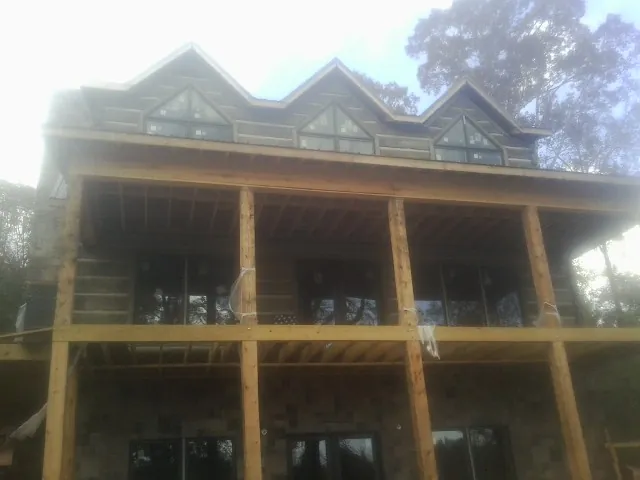 Dormers and porch framing on a large log home under construction — Roof Coating work by our crew in Robertsdale