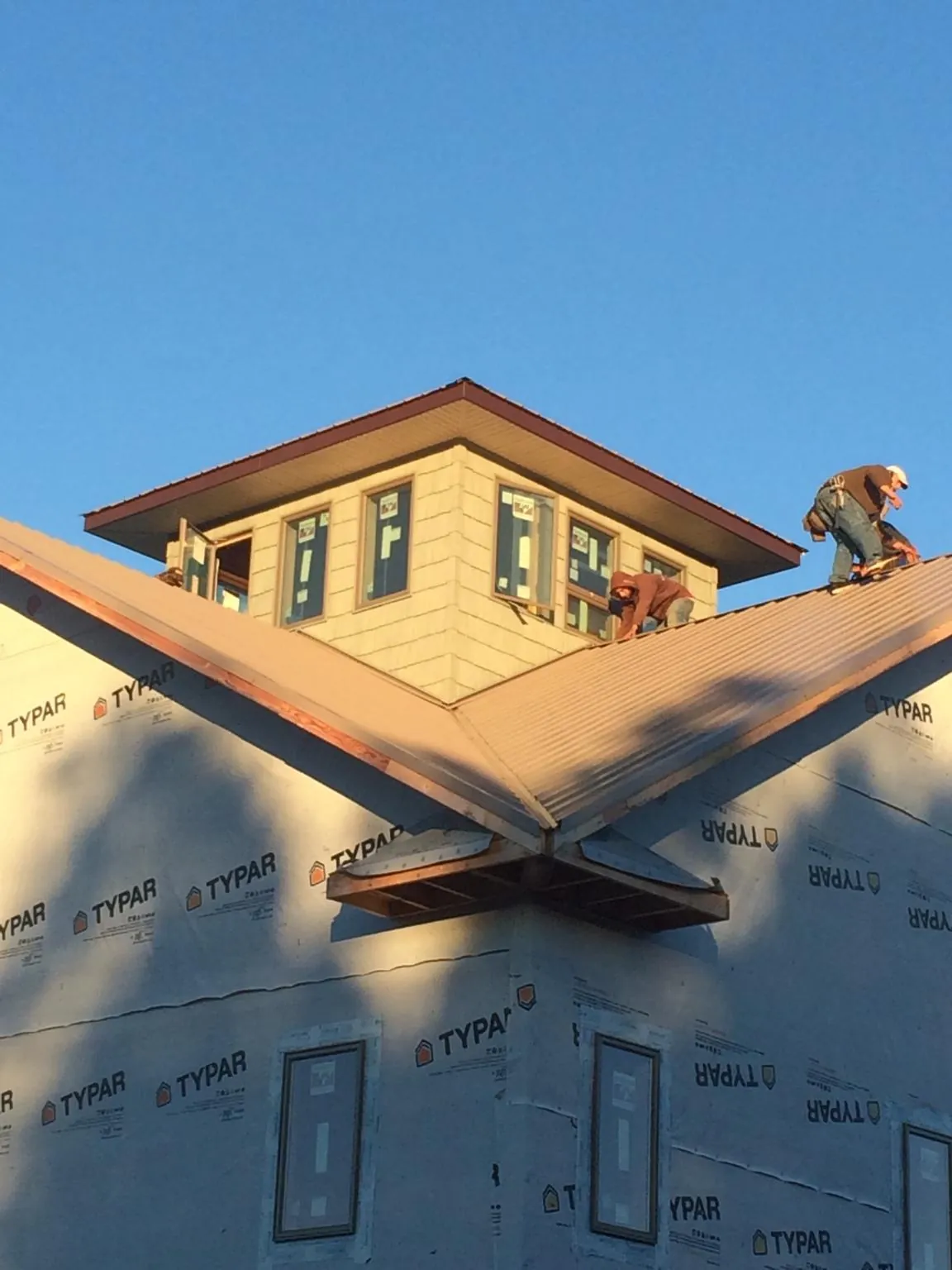 Roofers working around a rooftop cupola on a new metal roof at sunset — Roof Waterproofing in Robertsdale by Roofing Brothers